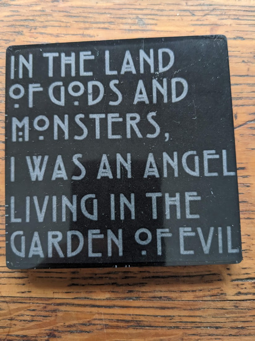a small square black block, with the engraved text: in the land of gods and monsters, i was an angel living in the garden of evil